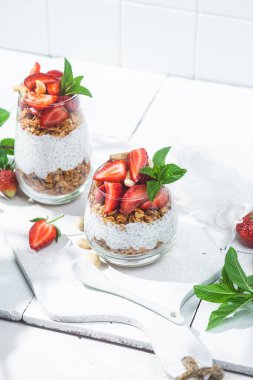 Beyaz arka planda yoğurtlu granola, chia ve çilek.