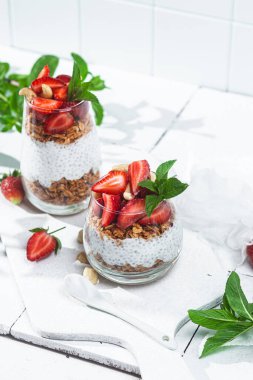 Beyaz arka planda yoğurtlu granola, chia ve çilek.