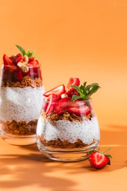 Yoğurtlu granola, chia ve çilekli parlak bir arka planda bir bardak