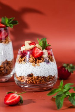 Yoğurtlu granola, chia ve çilekli parlak bir arka planda bir bardak