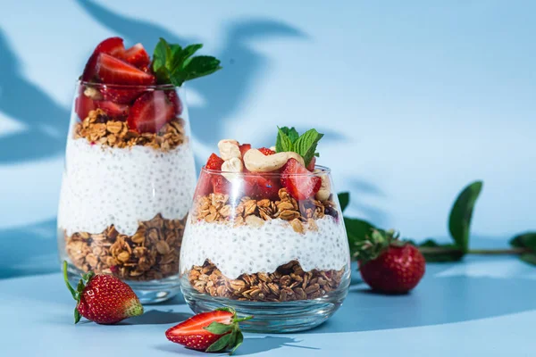 Yoğurtlu granola, chia ve çilekli parlak bir arka planda bir bardak