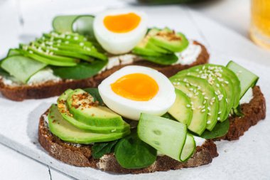 Krem peynirli sandviç, avokado ve beyaz arka planda haşlanmış yumurta.