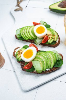 Krem peynirli sandviç, avokado ve beyaz arka planda haşlanmış yumurta.