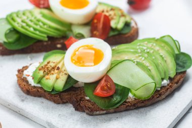 Krem peynirli sandviç, avokado ve beyaz arka planda haşlanmış yumurta.