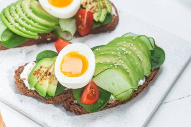 Krem peynirli sandviç, avokado ve beyaz arka planda haşlanmış yumurta.