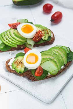 Krem peynirli sandviç, avokado ve beyaz arka planda haşlanmış yumurta.
