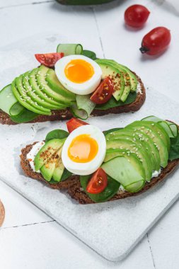 Krem peynirli sandviç, avokado ve beyaz arka planda haşlanmış yumurta.
