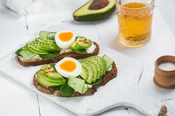 Krem peynirli sandviç, avokado ve beyaz arka planda haşlanmış yumurta.