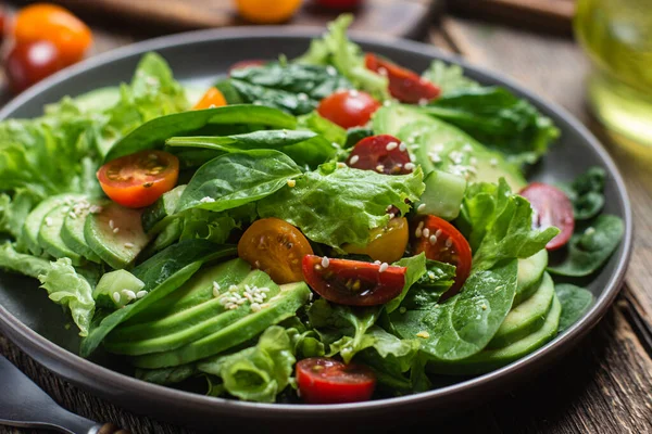 stock image Salad with spinach, avocado, tomatoes in a plate. Vegetarian salad