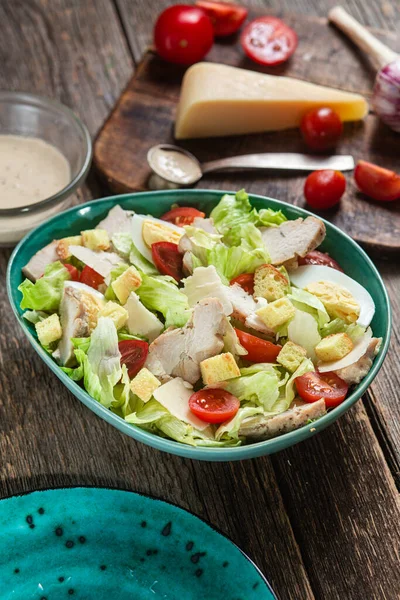 stock image Appetizing Caesar salad in a plate on a wooden table