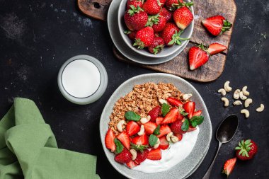 Yoğurtlu granola ve koyu arkaplanda çilek.