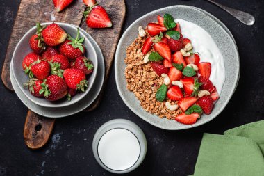 Yoğurtlu granola ve koyu arkaplanda çilek.