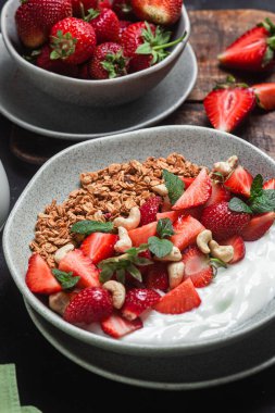 Yoğurtlu granola ve koyu arkaplanda çilek.