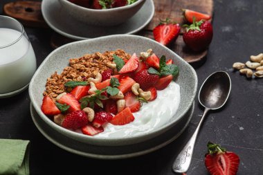 Yoğurtlu granola ve koyu arkaplanda çilek.