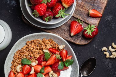 Yoğurtlu granola ve koyu arkaplanda çilek.