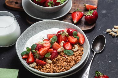 Yoğurtlu granola ve koyu arkaplanda çilek.