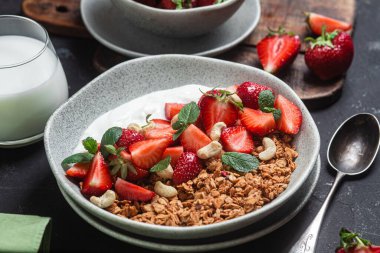 Yoğurtlu granola ve koyu arkaplanda çilek.