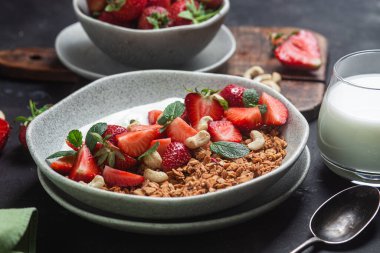Yoğurtlu granola ve koyu arkaplanda çilek.