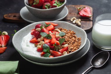 Yoğurtlu granola ve koyu arkaplanda çilek.