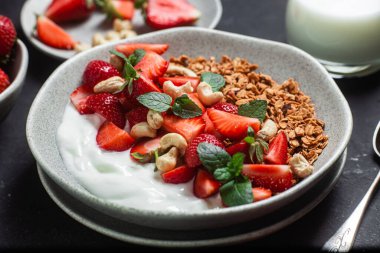 Yoğurtlu granola ve koyu arkaplanda çilek.