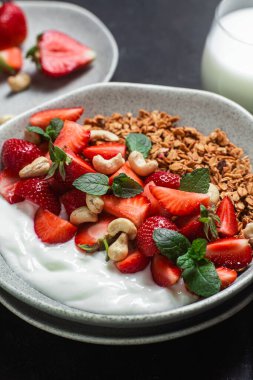 Yoğurtlu granola ve koyu arkaplanda çilek.