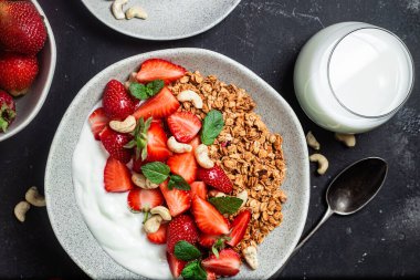 Yoğurtlu granola ve koyu arkaplanda çilek.
