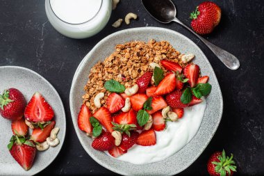 Yoğurtlu granola ve koyu arkaplanda çilek.