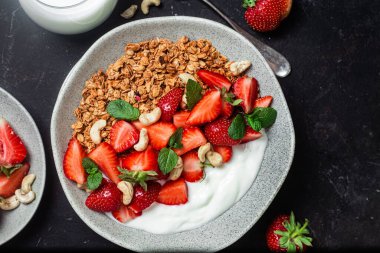 Yoğurtlu granola ve koyu arkaplanda çilek.