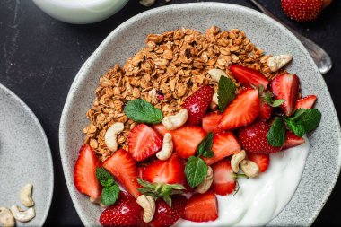 Yoğurtlu granola ve koyu arkaplanda çilek.