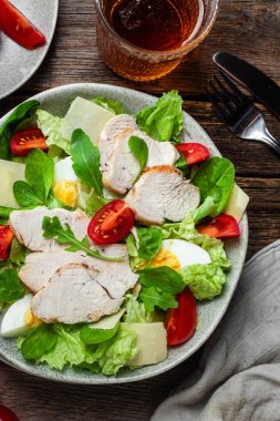 Tavuk fileto salatası, yumurta, domates ve peynir tabakta. Sezar salatası