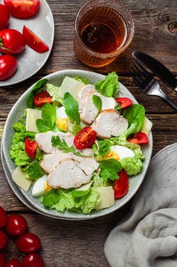 Tavuk fileto salatası, yumurta, domates ve peynir tabakta. Sezar salatası