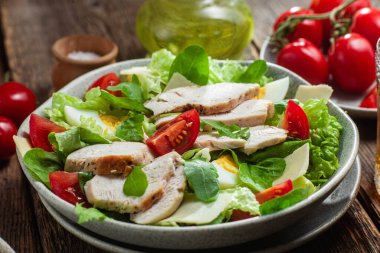 Tavuk fileto salatası, yumurta, domates ve peynir tabakta. Sezar salatası