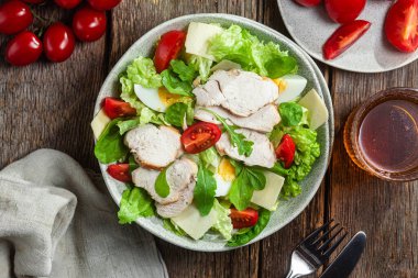 Tavuk fileto salatası, yumurta, domates ve peynir tabakta. Sezar salatası