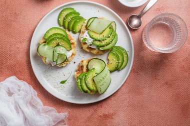 Krem peynirli waffle, bir tabakta avokado ve salatalık