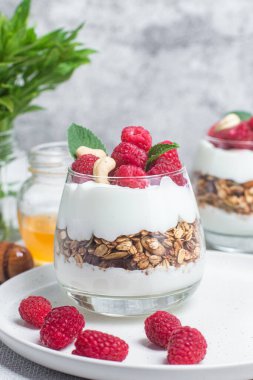 Yoğurtlu granola ve bir bardak ahududu.