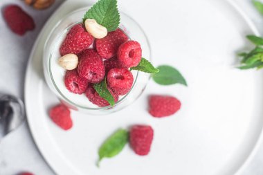 Yoğurtlu granola ve bir bardak ahududu.