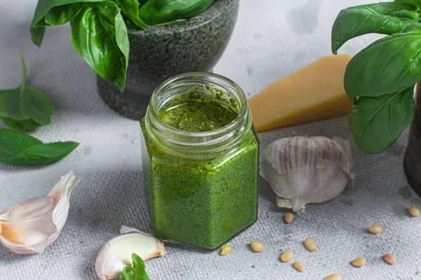 stock image Pesto sauce in a glass jar on the table. Basil