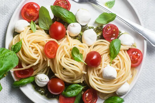 stock image Spaghetti with mozzarella, tomatoes, basil and pesto sauce. Pasta Caprese