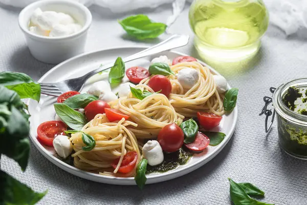 stock image Spaghetti with mozzarella, tomatoes, basil and pesto sauce. Pasta Caprese