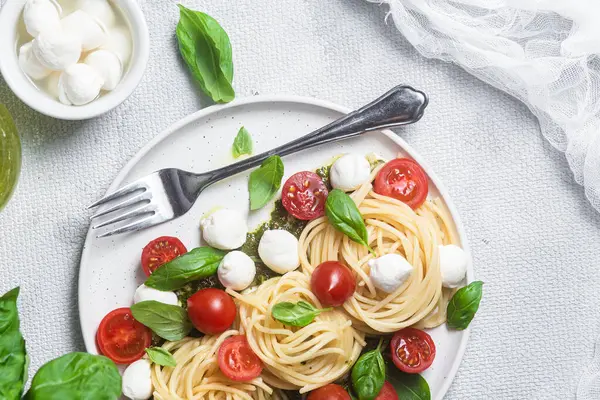 stock image Spaghetti with mozzarella, tomatoes, basil and pesto sauce. Pasta Caprese