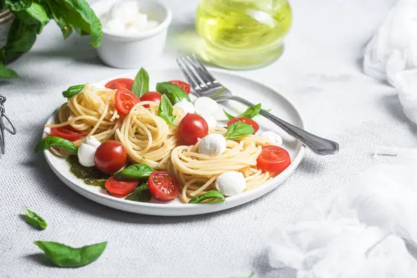 stock image Spaghetti with mozzarella, tomatoes, basil and pesto sauce. Pasta Caprese