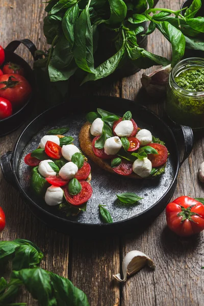 stock image Bruschetta with mozzarella, tomatoes, basil and pesto in a plate. Bruschetta Caprese