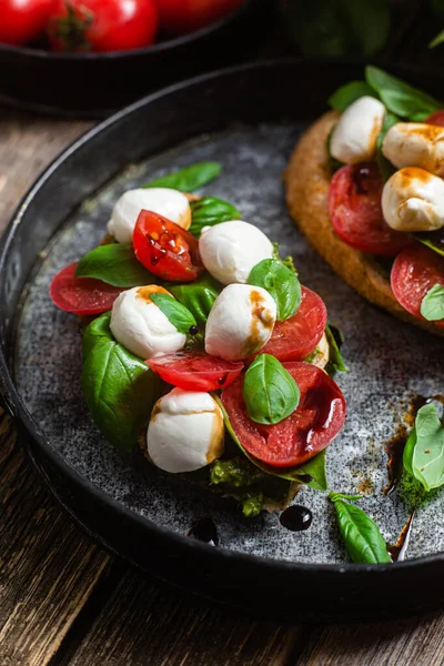 Stock image Bruschetta with mozzarella, tomatoes, basil and pesto in a plate. Bruschetta Caprese