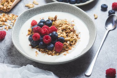 Yoğurtlu granola, ahududu, gri arkaplanda yaban mersini.