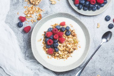 Yoğurtlu granola, ahududu, gri arkaplanda yaban mersini.