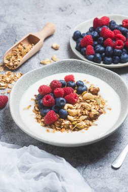 Yoğurtlu granola, ahududu, gri arkaplanda yaban mersini.