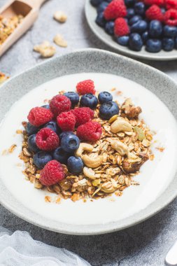 Yoğurtlu granola, ahududu, gri arkaplanda yaban mersini.
