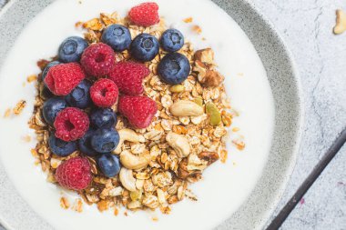 Yoğurtlu granola, ahududu, gri arkaplanda yaban mersini.