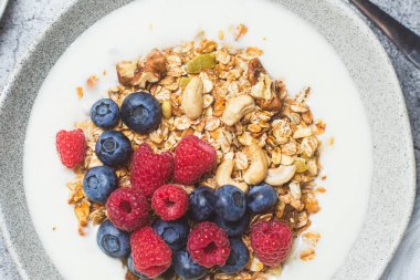 Yoğurtlu granola, ahududu, gri arkaplanda yaban mersini.