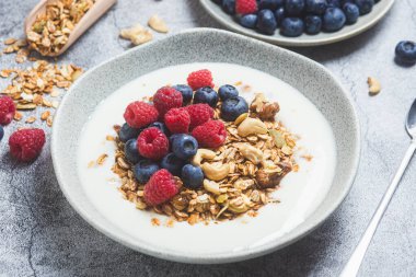 Yoğurtlu granola, ahududu, gri arkaplanda yaban mersini.